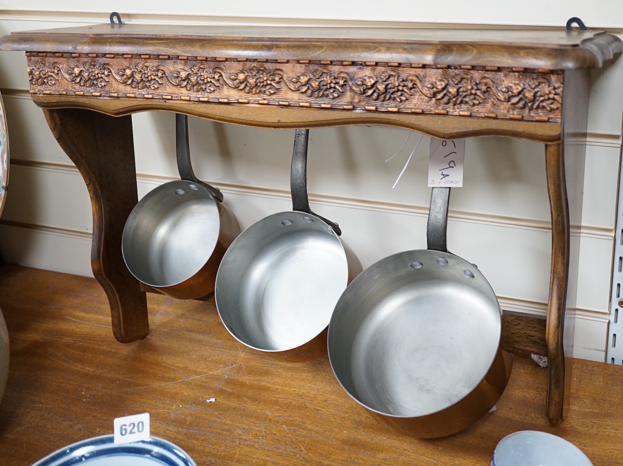 A set of three French copper saucepans, pendant from rack, 57cm wide